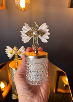 a person holding a small glass jar with a cross on it