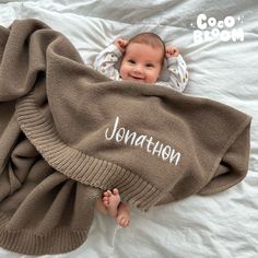 a baby laying on top of a bed under a blanket