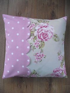 a pink and white flowered pillow with polka dot trim on it's side