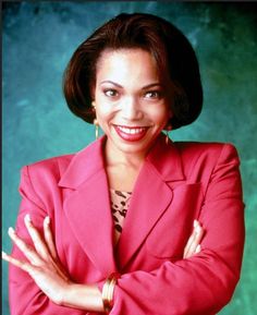 a woman in a red suit posing for a photo with her arms crossed and smiling