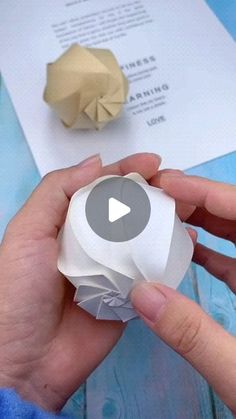 someone is holding an origami ball in their hand and making something out of paper