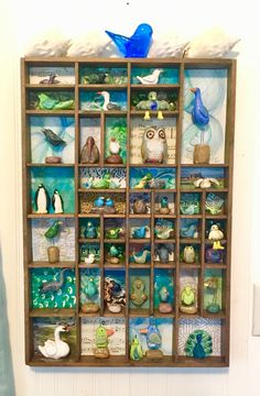 a wooden shelf filled with glass figurines on top of a white wall next to a toilet