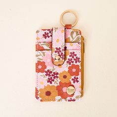 a pink flowered wallet with a gold ring hanging from it's front pocket