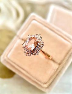 an engagement ring sits on top of a pink velvet box