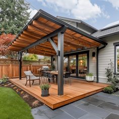 a patio with a table and chairs under a wooden awning next to a house