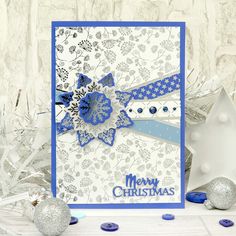 a blue and white christmas card with snowflakes on the table next to it