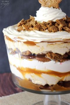 a layered dessert in a glass dish with a cookie on top