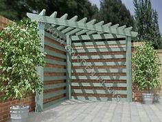 a large wooden gate in the middle of a brick wall with potted plants on either side