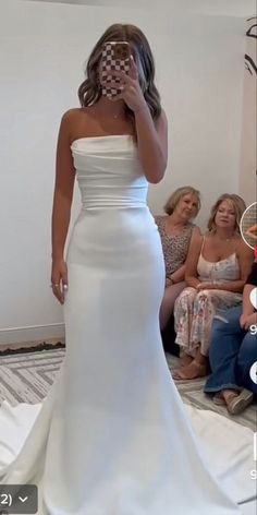 a woman in a white wedding dress is taking a selfie with her cell phone