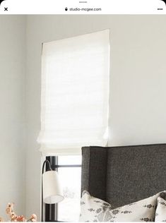 a bed with white sheets and pillows next to a window