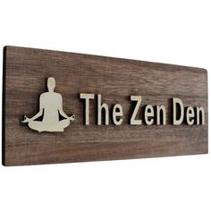 a wooden sign that says the zen den with a person sitting in a yoga pose