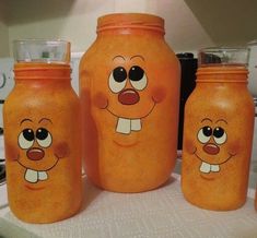 three orange jars with faces painted on them