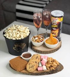 some snacks and drinks on a table with wine glasses, crackers, popcorn and ice cream