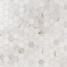 a white marble tile wall with hexagonal tiles on the top and bottom part