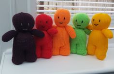 four knitted dolls sitting next to each other in front of a window sill