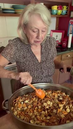 an older woman spooning food into a large pan