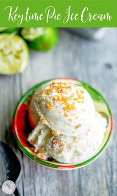 two scoops of ice cream sit in a small bowl on a wooden table next to sliced cucumbers