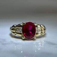 Beautiful red gemstone and diamond ring in a vintage like style and intricate gold band detailing. One large oval cut synthetic ruby centre stone, prong set. Two small pave set diamonds on each side of the centre ruby.  Pre-loved item. Stamped 14KT yellow gold.  Ring Size 9.25 US Weight: 5.110g **FREE shipping within Canada and USA** If you have any questions or concerns, please do not hesitate to contact us. We will be more than happy to help you and answer any inquiries.  We invite you to chec Classic Red Ruby Ring, Oval Cabochon, Classic Red Ruby Ring With Oval Cabochon, Classic Red Oval Diamond Ring, Elegant Ruby Rings With Oval Cabochon Center Stone, Ruby Rings With Center Stone, Oval Cabochon Shape, Oval Ruby Ring With Diamond Accents For Promise, Oval Diamond Ring With Lab-created Ruby Accents, Oval Ring With Lab-created Ruby And Accent Stones, Oval Lab-created Ruby Birthstone Ring With Center Stone