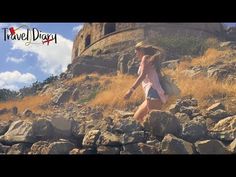 a woman walking on top of a rocky hillside