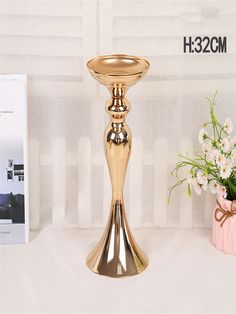 a gold candle holder sitting on top of a table next to a vase filled with flowers