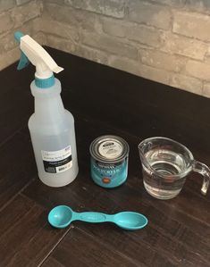 a bottle of cleaner, spoons and cup on a table