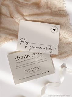 a thank you card with a white ribbon on top of it next to a piece of paper