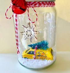 a glass jar filled with snow and a toy car in it's centerpiece