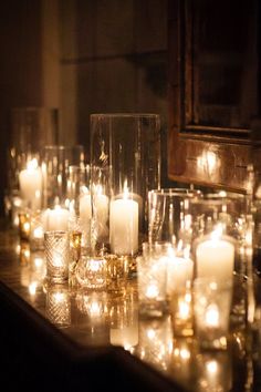 candles are lined up on a table with glass vases