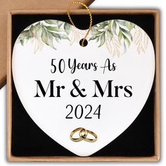 a white heart shaped ornament with two gold wedding rings on it and the words 50 years as mr and mrs