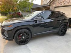 a gray suv parked in front of a house with black rims and red brake pads