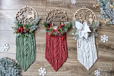 three christmas decorations are hanging on a wooden floor with snowflakes and evergreens