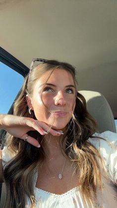 a woman sitting in the back seat of a car with her hand up to her face