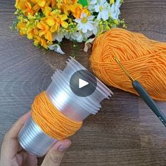 the yarn is being used to make an orange crochet afghan with flowers in the background