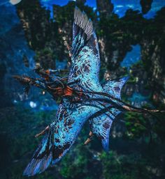 a blue bird flying through the air with trees in the backgrouds behind it