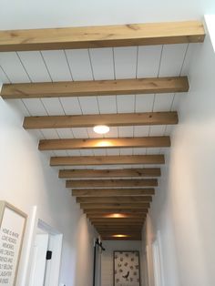 a hallway with white walls and wood beams on the ceiling is lit by a spot light