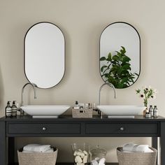 two sinks with mirrors on the wall above them and baskets under them in front of them