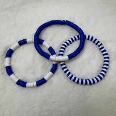 three blue and white bracelets sitting on top of a white blanket next to each other