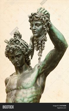 a bronze statue with grapes on his head and hands in the air, holding an object above his head