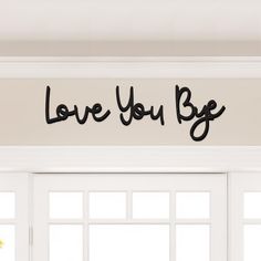 the word love you b e is written in black on a white wall above a window