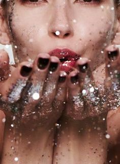 a woman with her hands in front of her face and water droplets all around her