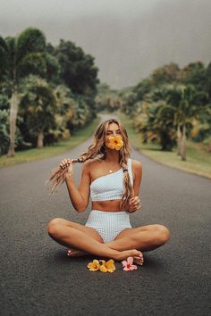 a woman sitting in the middle of a road with flowers on her face and hands