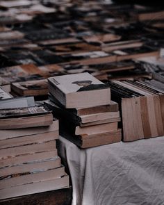 several stacks of books sitting on top of a white cloth covered table next to each other