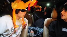 two young men sitting in the back of a car with stuffed animals on their heads