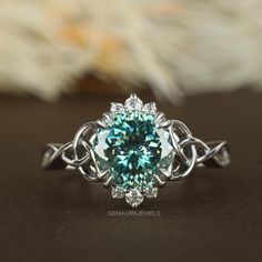 a fancy ring with a blue diamond surrounded by white diamonds on a black surface next to a flower