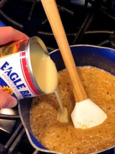 a person pouring sauce into a pan on top of the stove with a wooden spoon