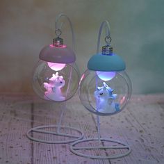 two clear glass ornaments with white and blue lights on them sitting on a wooden table