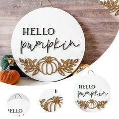 a white sign that says hello pumpkin and three pumpkins with leaves around it on a wooden background