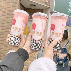 three people holding up two cups of bubble tea