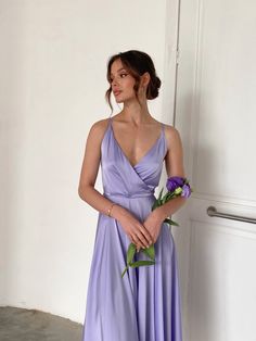 a woman in a purple dress holding flowers