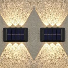 two lights that are on the side of a wall with some sort of solar panel